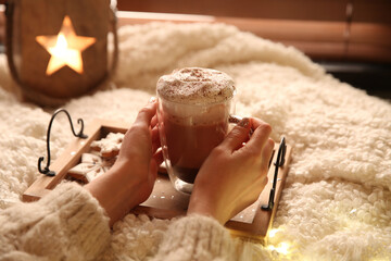 Woman with cup of hot drink and Christmas cookies at home, closeup