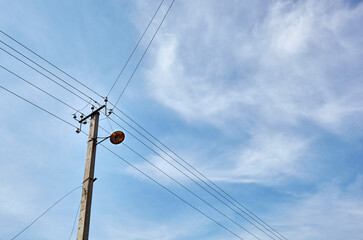 Power line post with electricity cables against a clear blue sky
