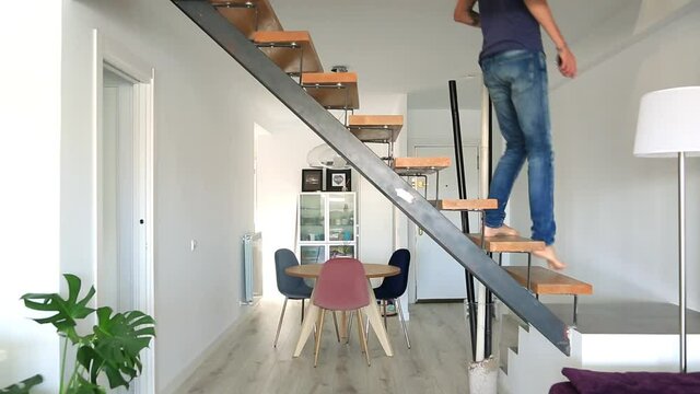 Young Man Walking Down The Stairs And Walking Home In Jeans And Blue T-shirt