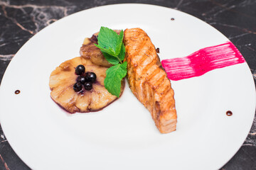 Delicious salmon fillet with caramelized pineapple and berries on a white plate