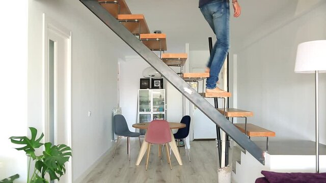 Young Man Walking Down The Stairs And Walking Home In Jeans And Blue T-shirt