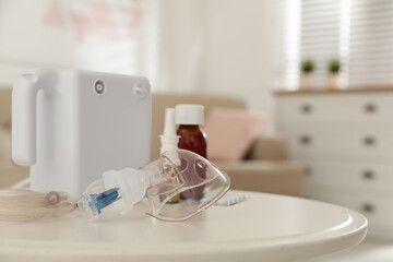 Modern nebulizer with face mask and medications on white table indoors. Inhalation equipment