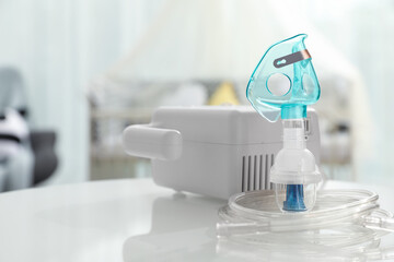 Modern nebulizer with face mask on white table in children's room. Equipment for inhalation