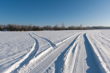 Fototapeta na wymiar Winter. Sunny day. Car road or track on a snowy field.
