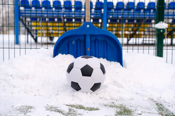 Classic soccer ball, snow-covered football field and shovel on winter stadium outdoor © Serhii