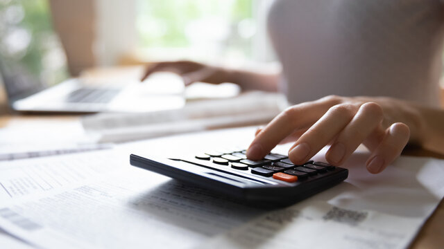 Calculating expenses. Close up of young female hand counting on portable electronic calculator estimating money income. Housewife planning family budget or managing payments for utility services.