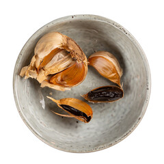 Black garlic in gray bowl isolated on white. Top view.