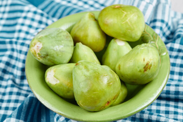 A bowl of juicy green figs on a blue tablecloth