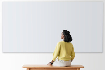 Woman looking at blank wall rear view - Powered by Adobe