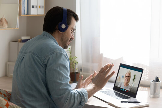Teleeducation. Focused young man in headset take distant lesson at senior female teacher listen to new material. Remote student look on pc screen asking questions old lady tutor via video conference