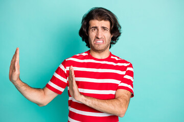 Portrait of nice terrified brown-haired guy showing stop sign aside dont isolated over bright green turquoise color background