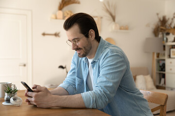 Web mining. Concentrated millennial male stay at home on weekend engaged in playing mobile game on cellphone screen. Focused young guy browsing web enjoying chatting online using social media apps