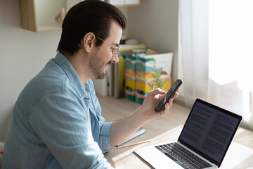 Data synchronization. Young man freelancer sitting by desk at home office make information exchange...