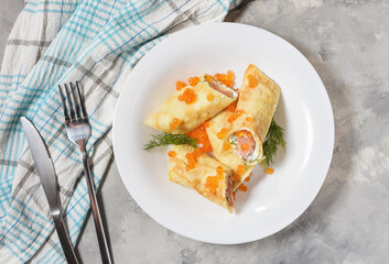 Delicious breakfast - crepes with smoked salmon, sour cream and caviarch on concrete background.