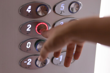 Finger of a woman's hand pressing an elevator button