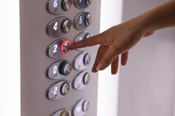 Finger of a woman's hand pressing a lift button