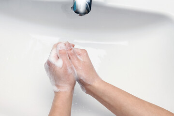 A Hands with soap are washed under the tap with water. Clean from infection and dirt and virus. At home or in the hospital ablution office.