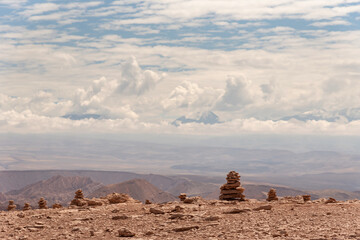 Stone stacks located against rocky formations and cloudy sky in Atacama Desert, Chile