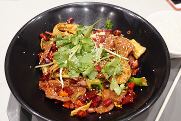 Mala Xiang Guo - Chinese popular dish, stir fried assorted mixed vegetables, mushroom and meat in hot chilli seasoning on big black bowl