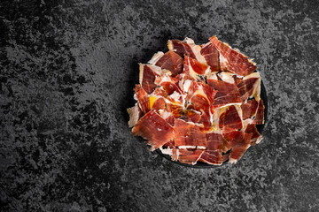 Top view of jabugo serrano ham slices, Dry Spanish ham. Typical spanish breakfast concept. Black background 