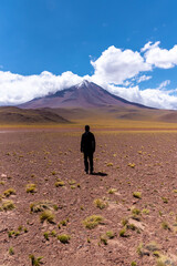 Silhouette of unrecognizable man admiring snowy Licancabur volcano on cloudy day in Atacama Desert, Chile