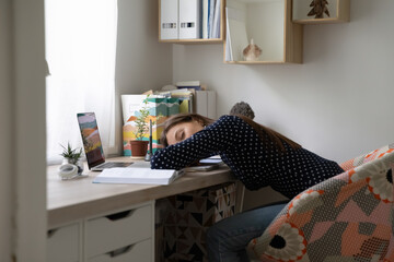 Work was too hard. Exhausted young woman freelancer napping by home office desk after difficult long workday. Fatigued teen student lying on papers before laptop falling asleep while preparing to exam