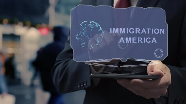 Unrecognizable businessman uses hologram on smartphone with text Immigration America. Man in shirt and jacket with holographic screen on background of entrance to the airport or train station