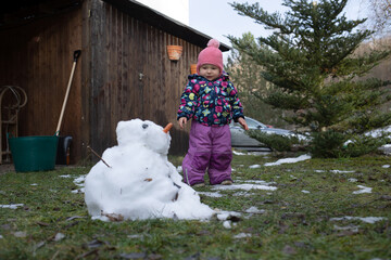 Frühlingsbeginn  - Kind steht vor geschmolzenen Schneemann