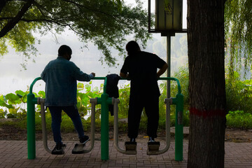 In the early morning, a Chinese couple used sports equipment to exercise by the park river.