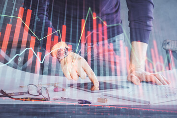 Double exposure of man's hands holding and using a digital device and forex graph drawing. Financial market concept.
