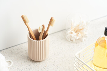 Cup with bamboo toothbrushes near soap and swabs