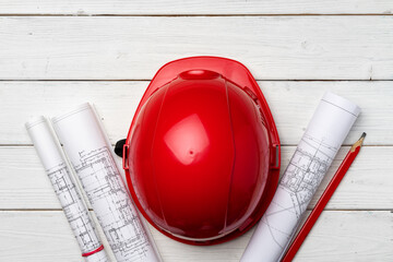 Hardhat and blueprints on wooden background top view
