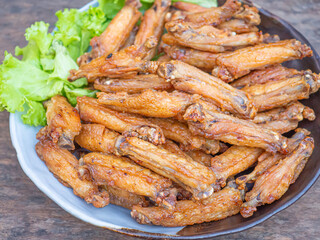 Fried chicken wings with fish sauce with salad vegetables on a white plate placed on a wooden table. Close-up photo. Space for text. Concept of foods