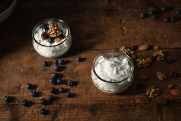cup of greek yogurt with blueberries and mixed nuts on wooden table
