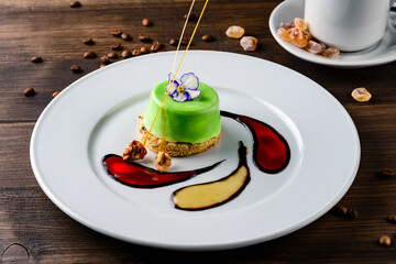 Decorative dessert food. Beautiful green cake decorated served on round plate in Italian restaurant. Delicious desserts