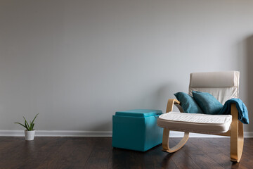 Relax atmosphere room with  hardwood parquet floor and celery colored wall with a rocking chair and teal color thrown blanked placed on the armrest. Cactus and an ottoman.