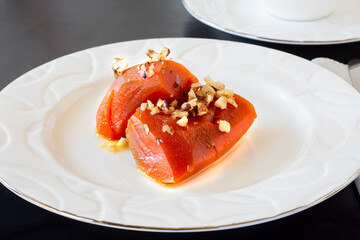 Pumpkin dessert with walnut sprinkles cooked with steamed sugar, top view on a white plate .