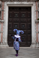 Fototapeta na wymiar Masked man in ornate costume at the the Venetian masquerade stands near St. Mark's Square in Venice
