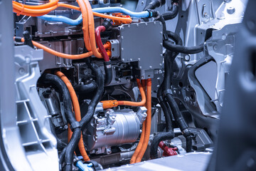 Chassis of the electric car with powertrain and power connections closeup. Blue toned. EV car drivetrain at maintenance.
