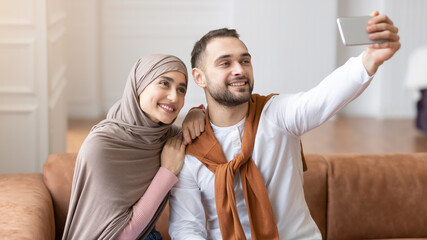 Cheerful Muslim Spouses Making Selfie On Mobile Phone At Home