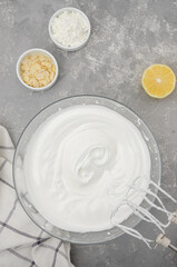 Cooking meringue Pavlova roll cake. Whipped egg whites with sugar in a bowl on a gray concrete background. Recipe step by step. Vertical, Top view.