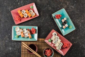 Obraz na płótnie Canvas Several plates of sushi rolls served by the chef on a dark background.