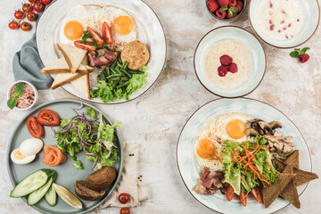 Several dishes with scrambled eggs, boiled egg, porridge with rice and oats on the plates