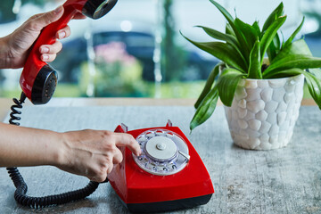 Hand dialing the number on telephone in the marble background