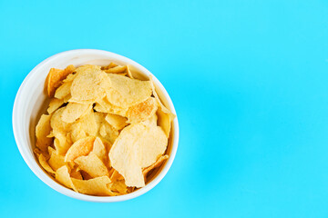 Bowl of crispy chips on blue background