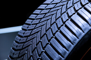 Clean Tyre, black new shiny car tire. Dark background.
