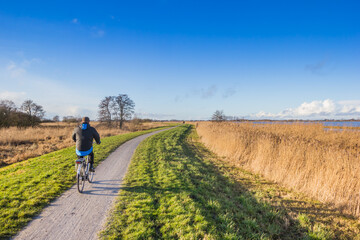 Fototapeta na wymiar Man riding his bike at the Schildmeer lake in Groningen, Netherlands
