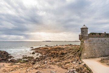 Sunset over the Atlantic ocean. Medieval watchtower of fort of Sao Francisco do Queijo in Porto,...