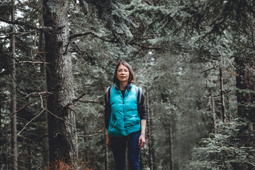 Obraz premium Young woman hiking through an evergreen forest in the mountains