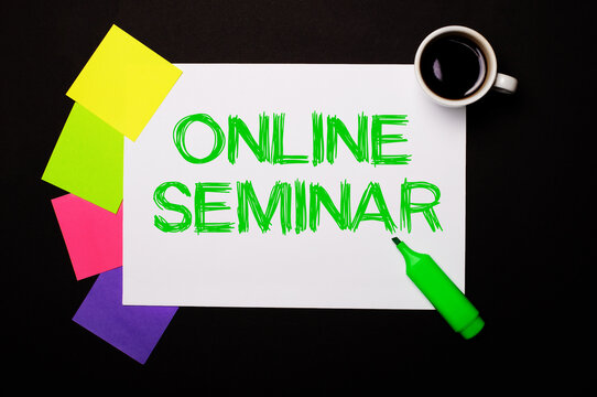 A sheet of paper with the inscription ONLINE SEMINAR, a cup of coffee, bright multi-colored stickers for notes and a green marker on a black background. View from above.